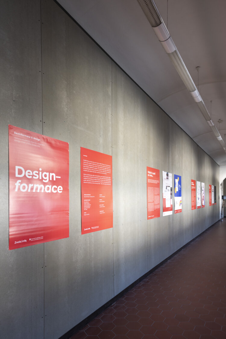 A view of the wall with red posters with white lettering depicting an exhibition on desinformations


